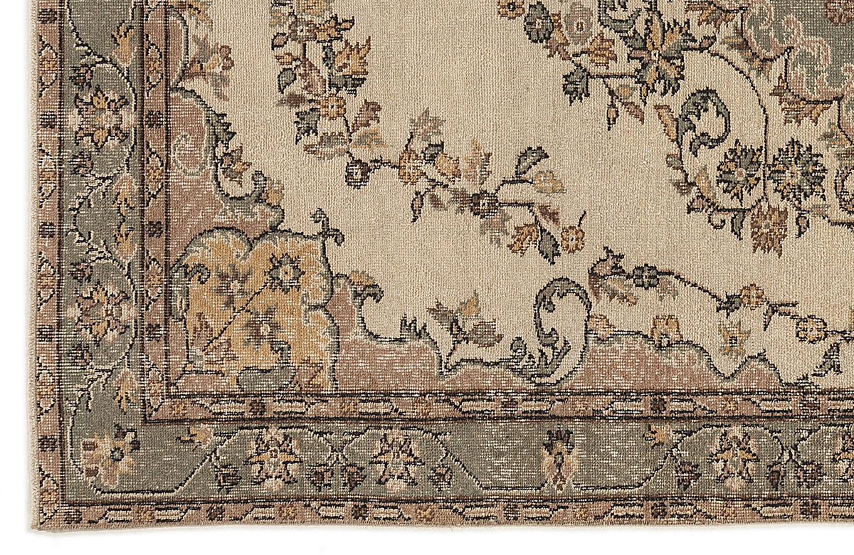 Beige rug with a sage green border and traditional floral medallion pattern in muted tones of brown, gold, and grey.