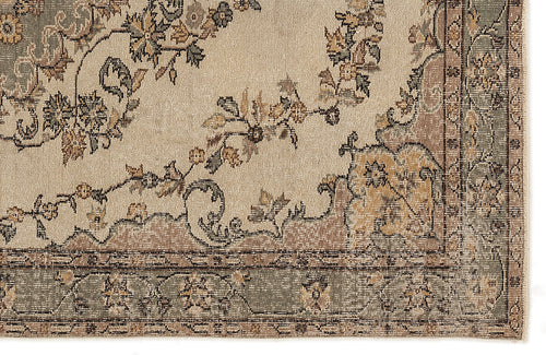 Load image 1 in gallery view. Beige rug with a distressed floral pattern in muted sage green and brown, featuring a decorative border.