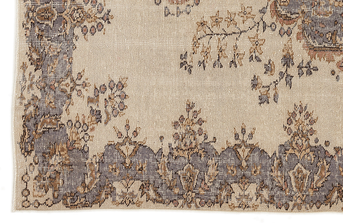 Beige rug with a distressed grey and brown floral border and scattered botanical motifs.