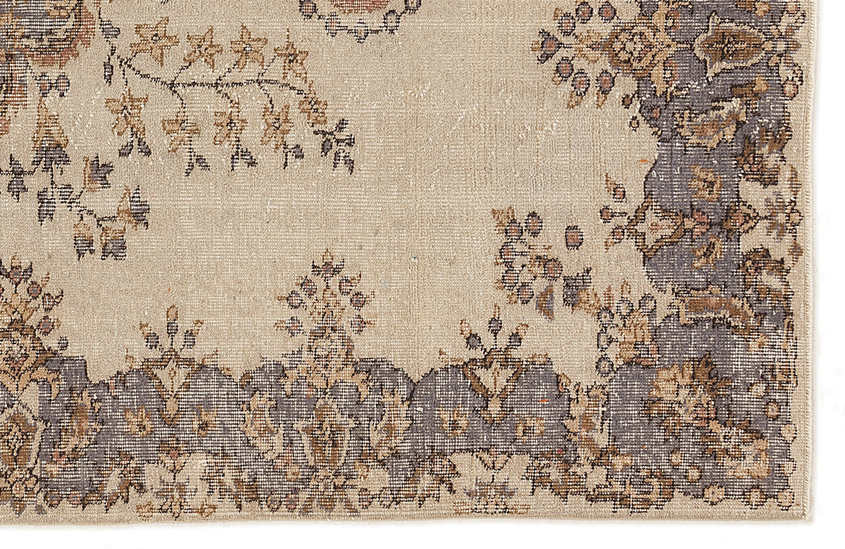 Beige rug with a distressed floral medallion pattern in charcoal, tan, and muted brown tones.