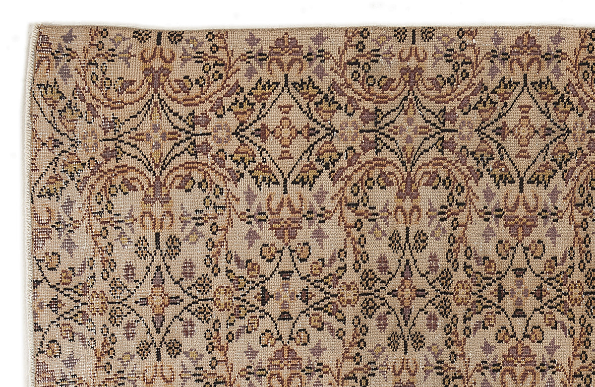 Beige rug with a repeating brown and muted purple floral medallion pattern on a white background.