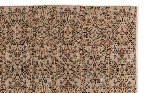 Load image 1 in gallery view. Tan rug with a repeating geometric floral medallion pattern in shades of brown, charcoal, and muted blue.