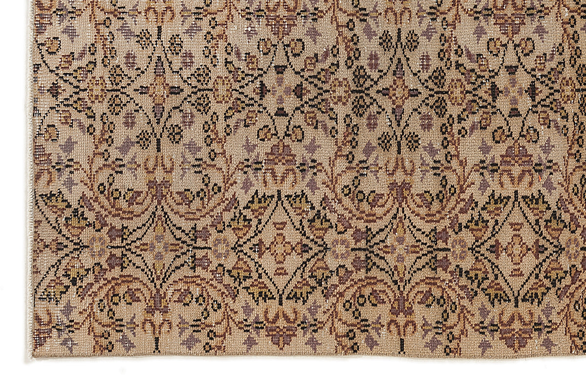 Beige rug with a repeating black, brown, and muted purple floral medallion pattern in a distressed, vintage style.