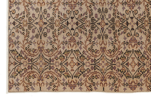 Load image 1 in gallery view. Beige rug with a repeating black, brown, and muted purple floral medallion pattern in a distressed, vintage style.