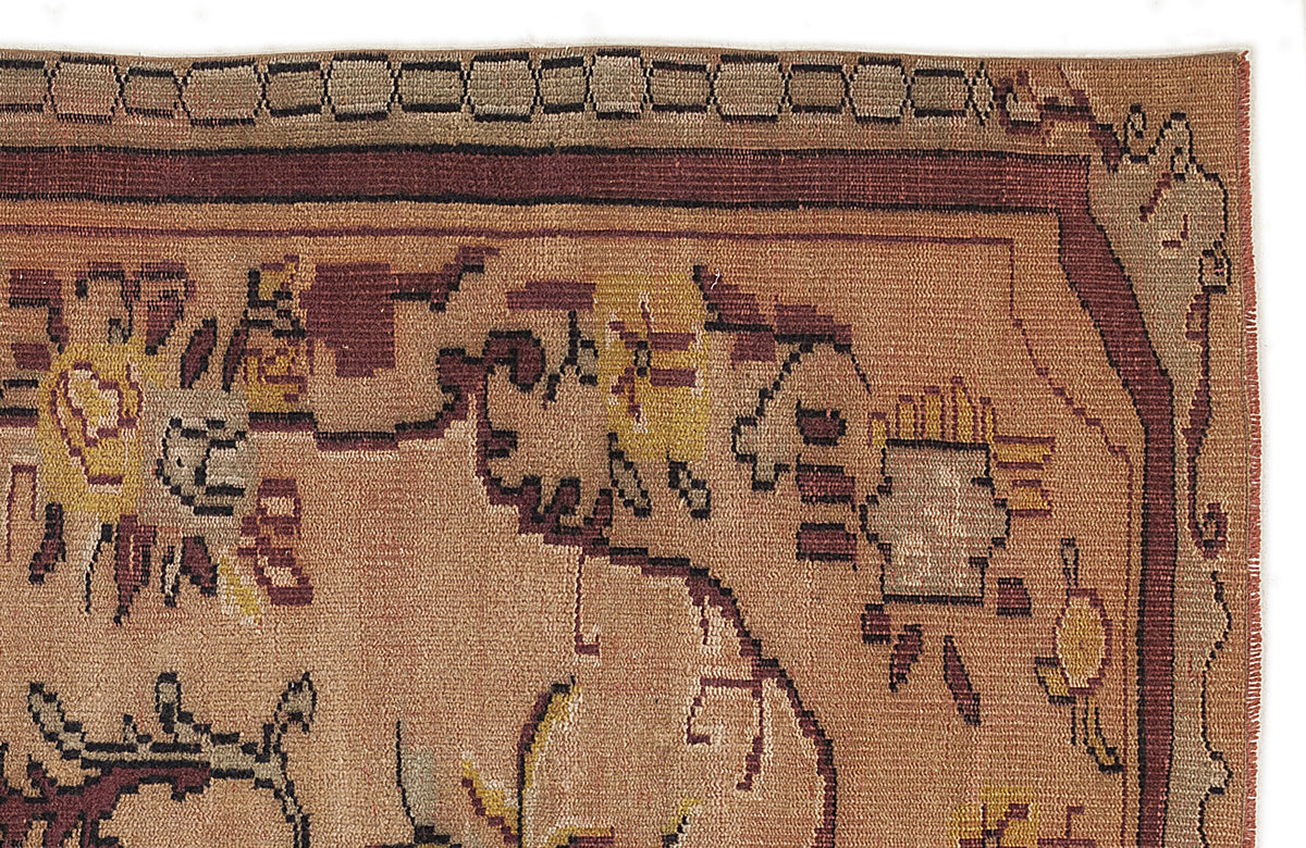 Tan and brown hand-knotted rug with a geometric border and stylized floral motifs on a white background.