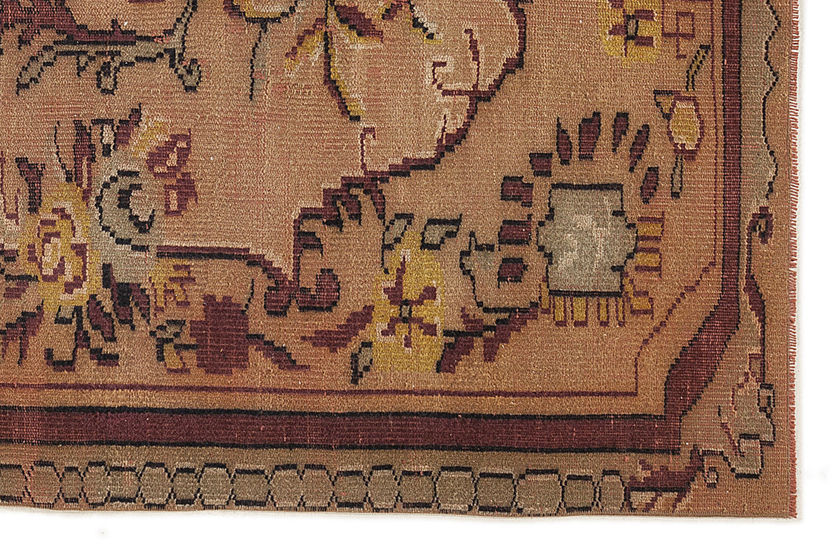 Brown traditional rug with a geometric border and stylized floral motifs in mustard, maroon, and grey.