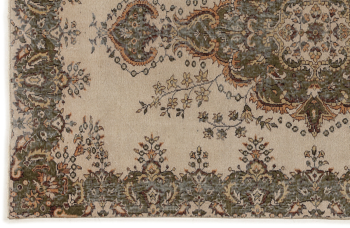 Beige rug with a traditional olive green and rust-colored floral medallion and border pattern.