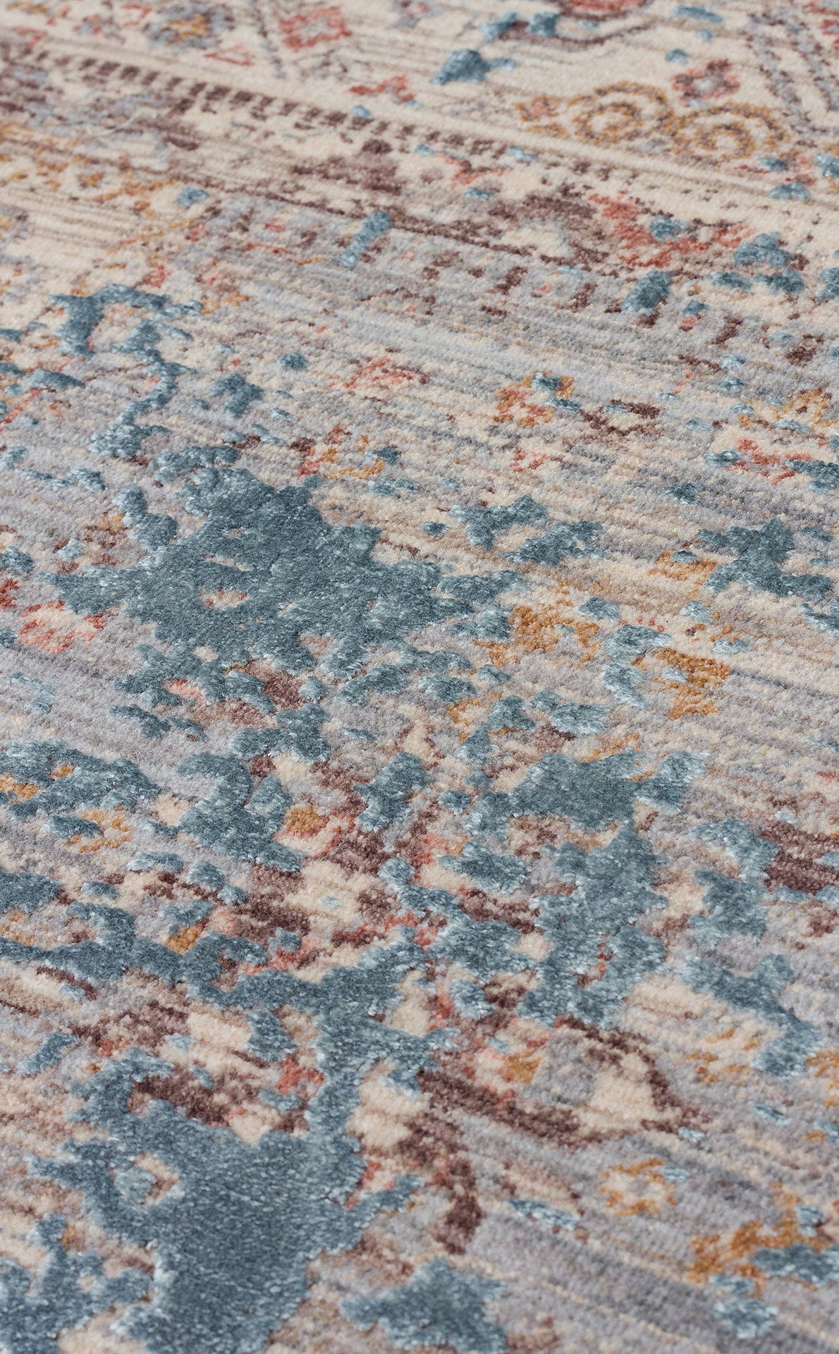 Distressed area rug with a faded traditional medallion pattern in shades of blue, cream, rust, and brown.