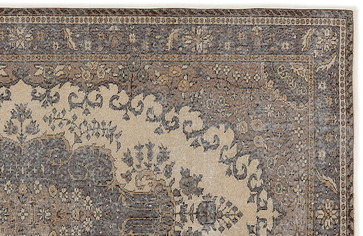 Dark brown and beige rug with a traditional distressed floral medallion pattern and a detailed border.