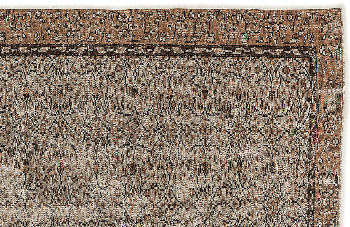 Tan and dark brown rug with a traditional floral border and a repeating geometric medallion pattern.