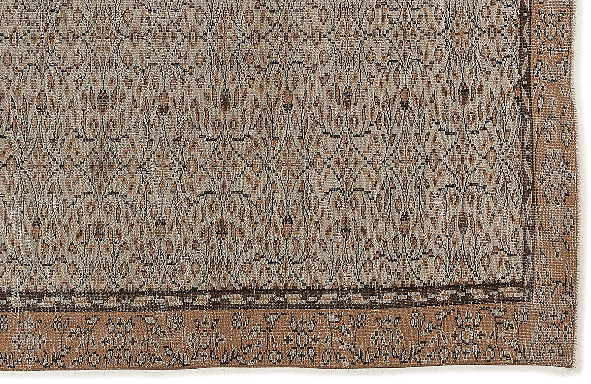 Tan and brown rug with a dense, distressed geometric pattern and a wide decorative border.