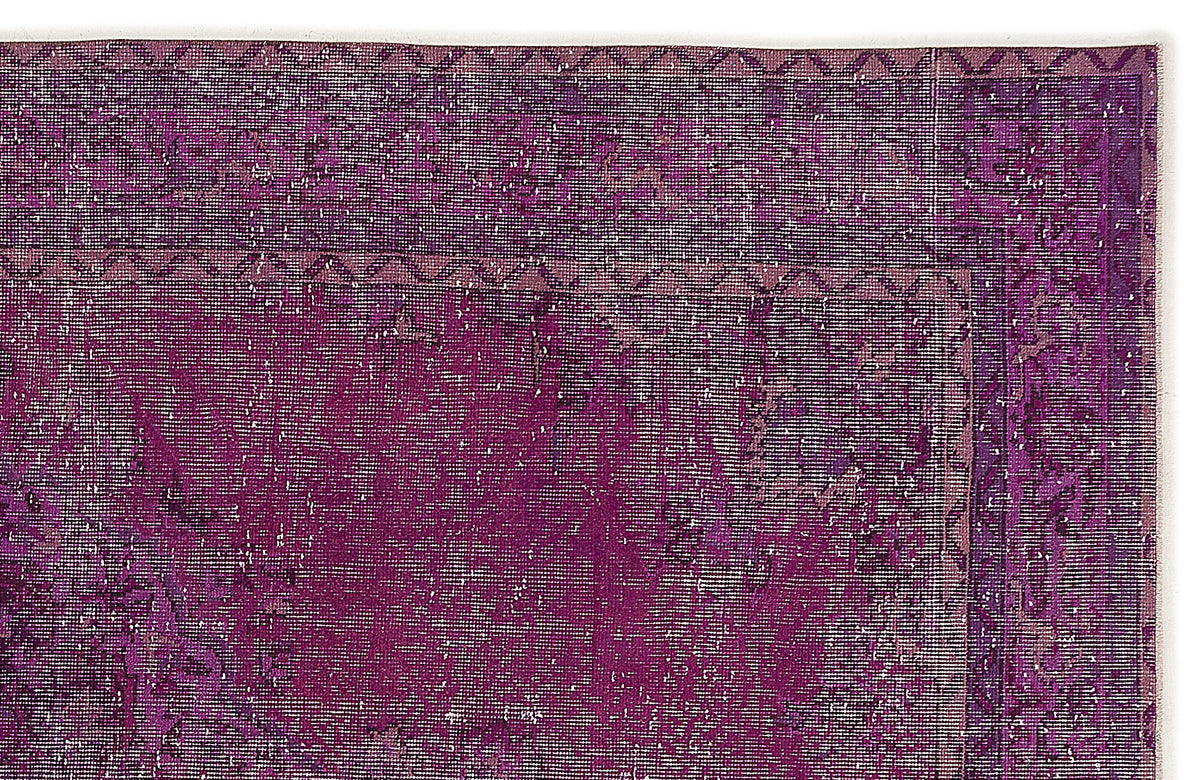 Deep purple distressed rug with a geometric border and faded, worn-in texture.
