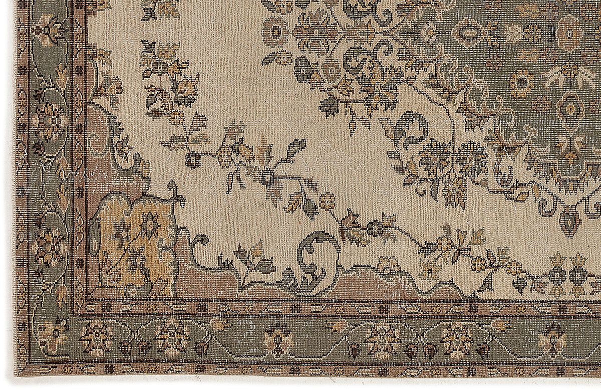 Beige rug with a sage green and brown traditional floral medallion pattern and a decorative border.