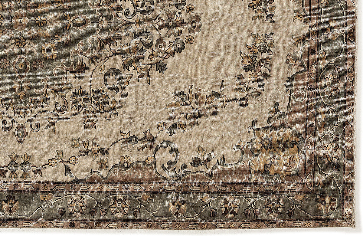 Beige rug with a sage green and brown floral medallion pattern and a detailed botanical border.