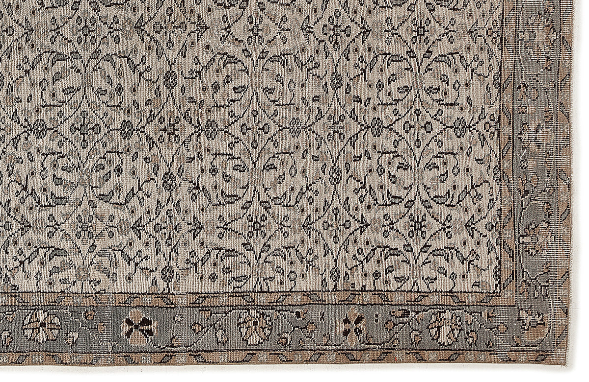 Grey and beige vintage-style rug with a repeating floral medallion pattern and a detailed border.