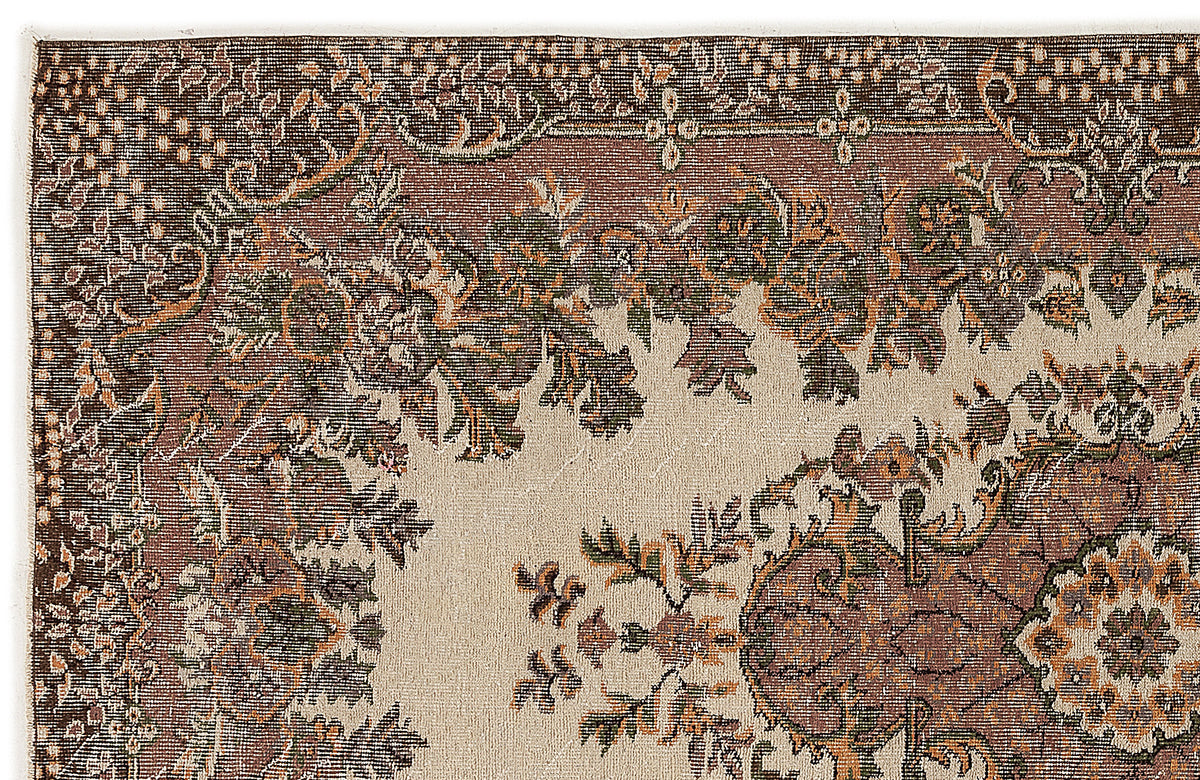 Close-up of a traditional rug with a beige field, featuring brown, green, and orange floral and medallion motifs.