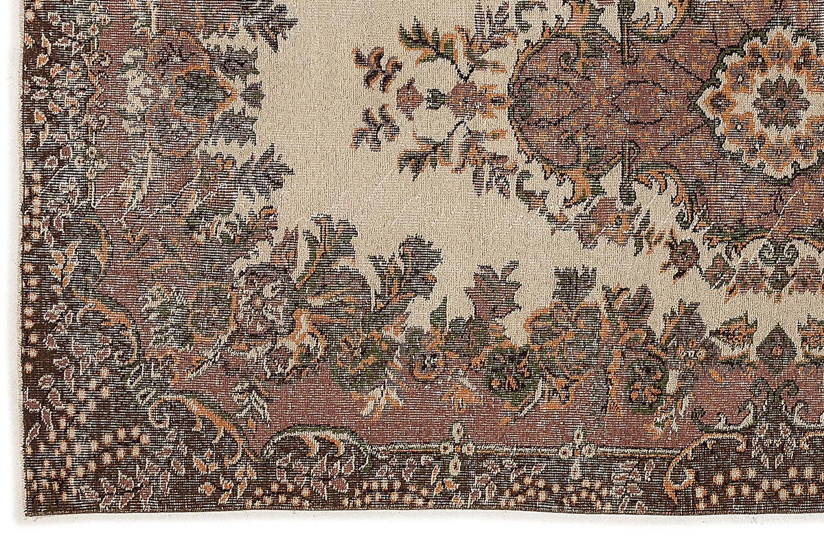 Beige rug with a distressed traditional floral medallion pattern in brown, olive green, and rust orange.
