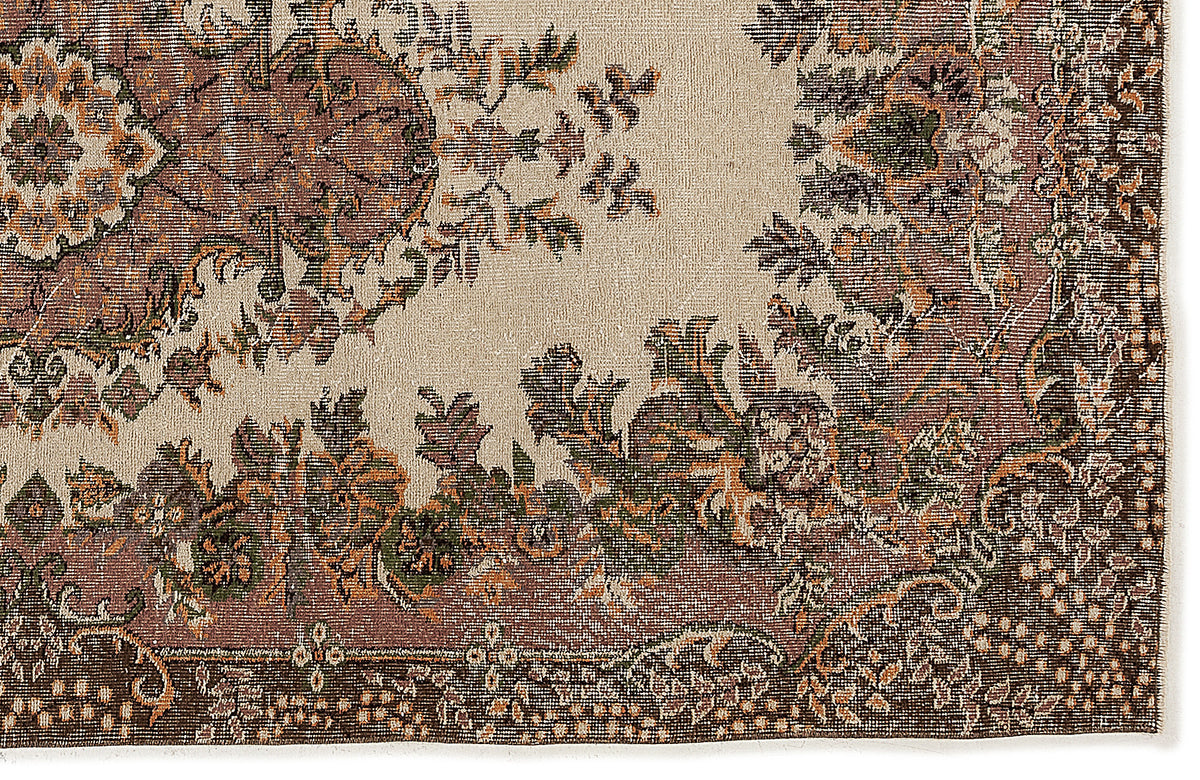 Beige rug with a distressed traditional floral medallion pattern in shades of brown, rust, and dark green.