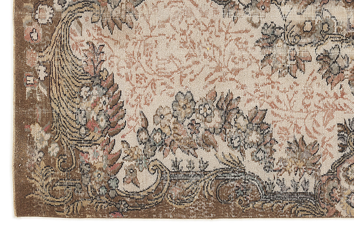 Beige and brown traditional rug with a distressed floral medallion pattern and ornate border.