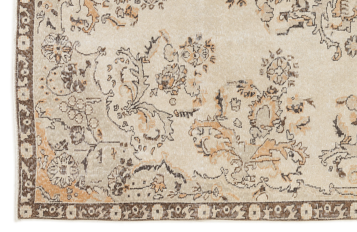 Beige rug with a distressed floral pattern in brown and tan, featuring a dark brown geometric border.