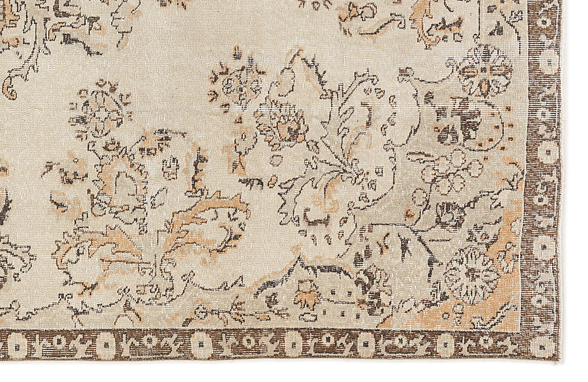 Beige and tan rug with a distressed floral pattern and a dark brown geometric border.