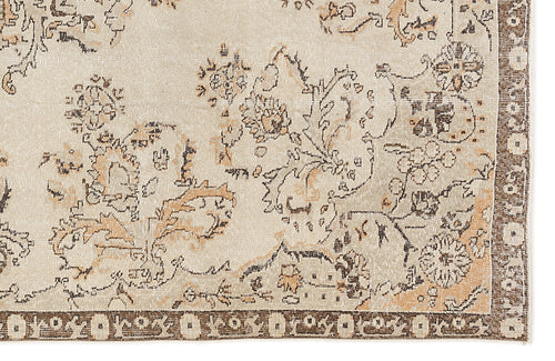 Load image 1 in gallery view. Beige and tan rug with a distressed floral pattern and a dark brown geometric border.