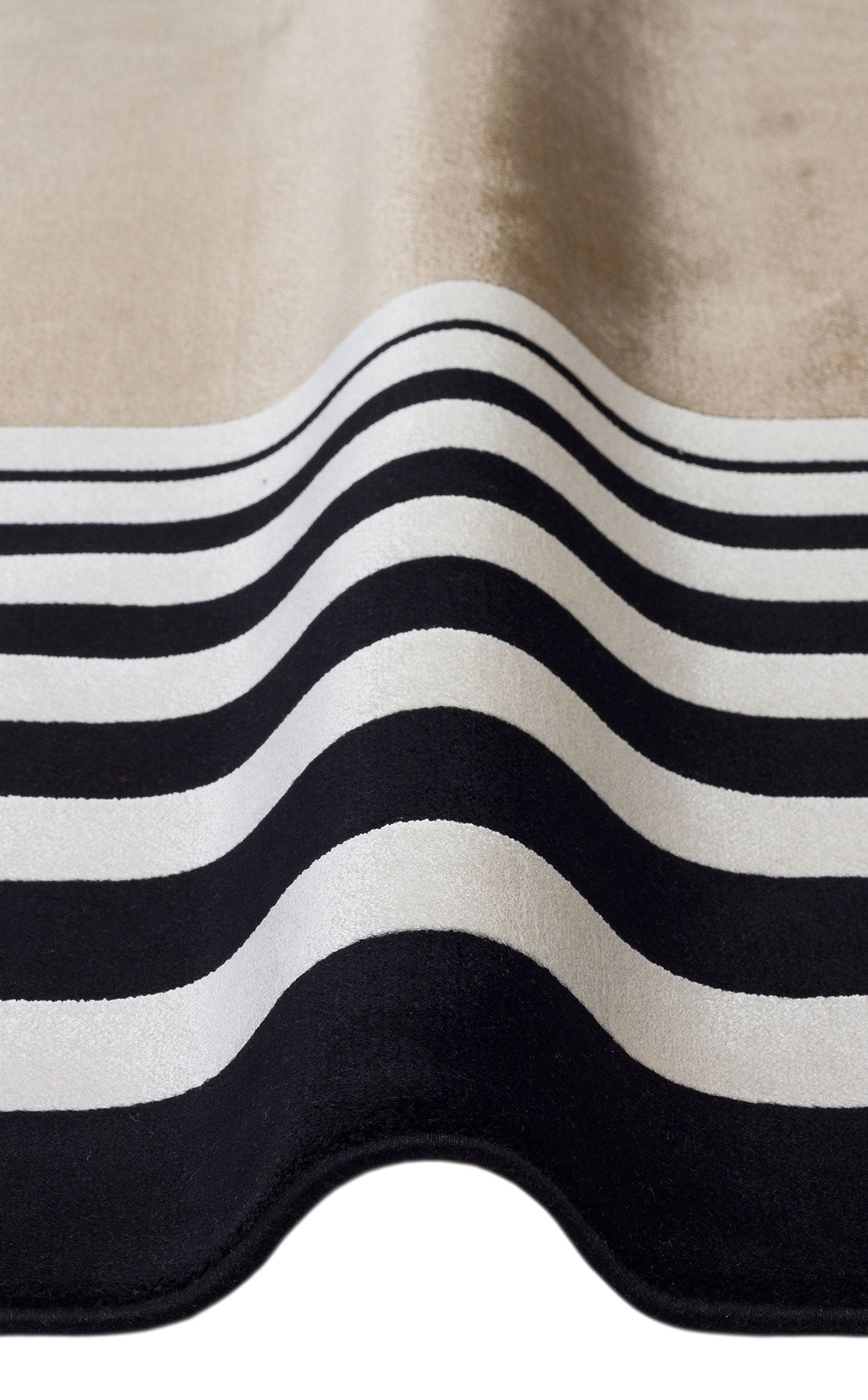 Folded rug featuring a black and white horizontal striped pattern transitioning into a solid beige section.