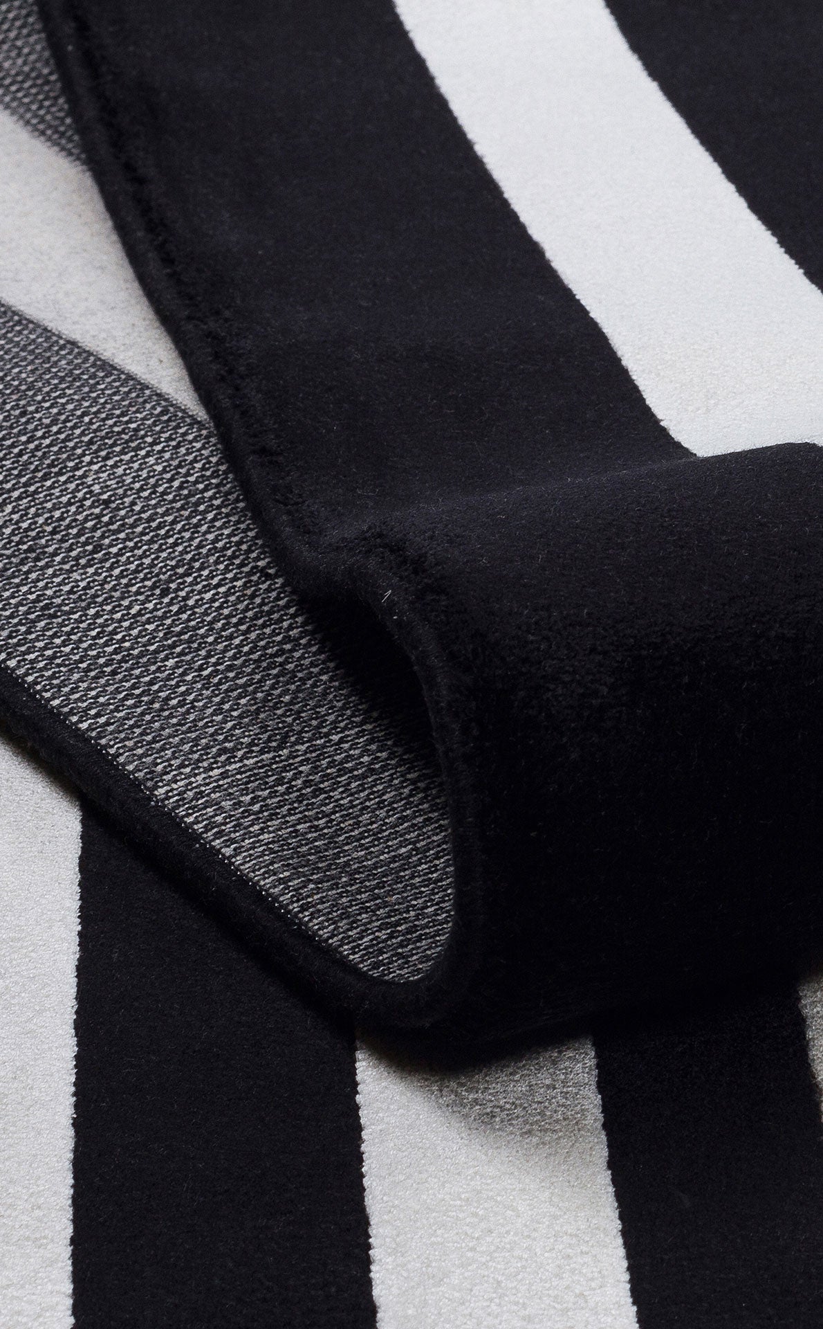 Black and white striped rug with a folded corner showing a textured, woven backing.