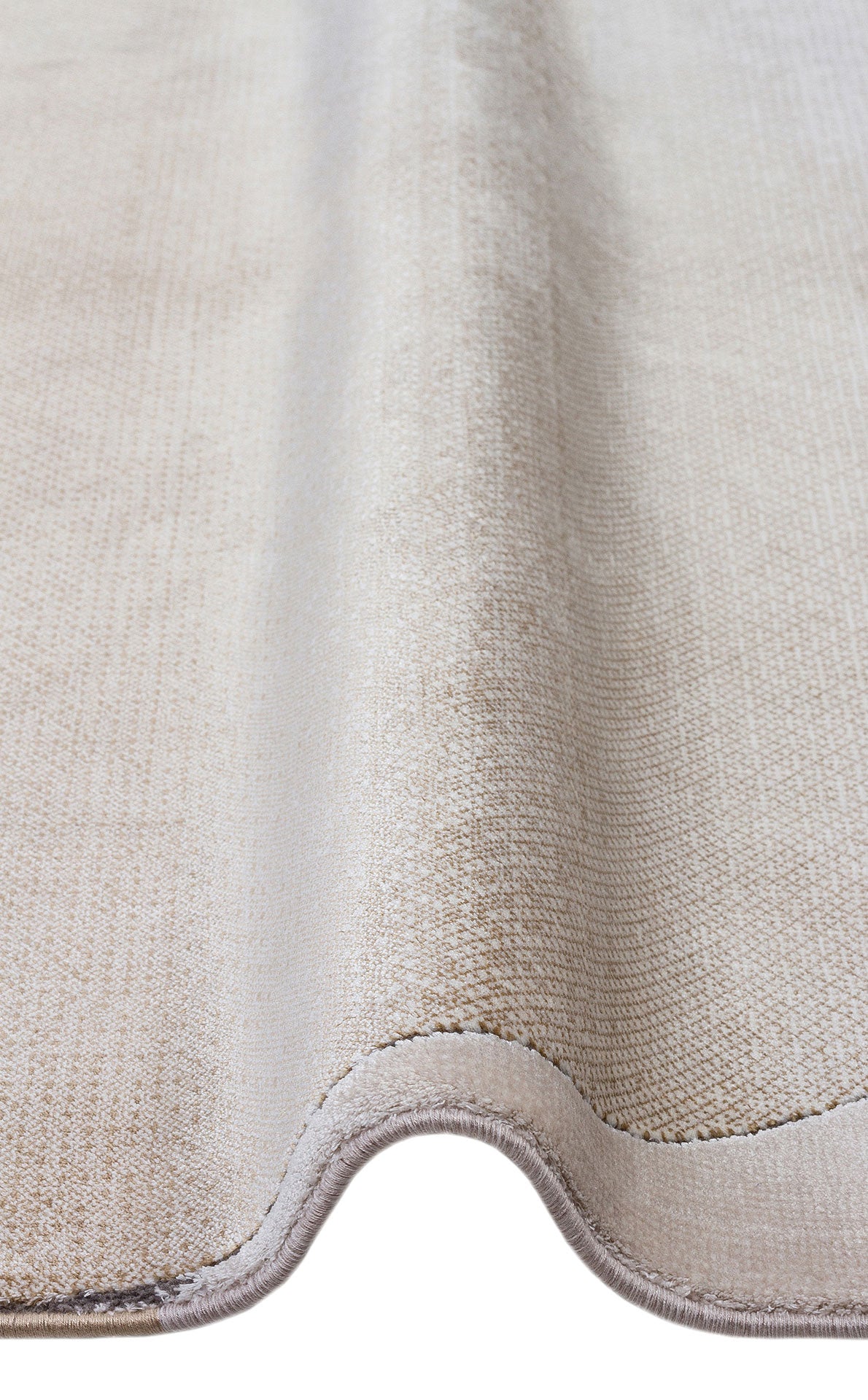 Solid beige textured rug with a soft pile and finished bound edges, shown folded against a white background.
