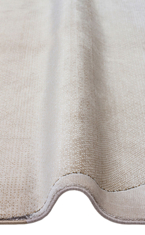 Load image 1 in gallery view. Solid beige textured rug with a soft pile and finished bound edges, shown folded against a white background.