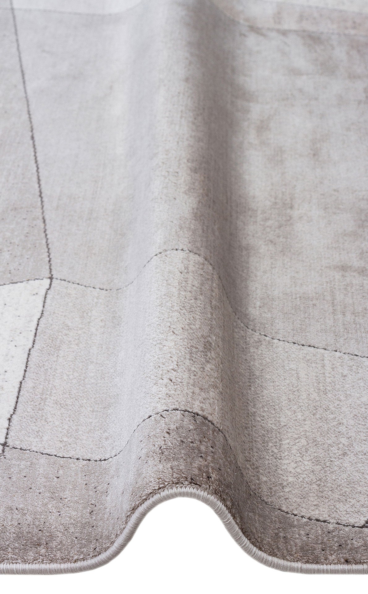 Light gray rug with a subtle grid pattern and soft, distressed texture, shown in a folded close-up view.