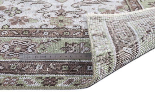 Load image 1 in gallery view. Distressed sage green and brown traditional rug with a folded corner and a metal ruler for scale on a white background.