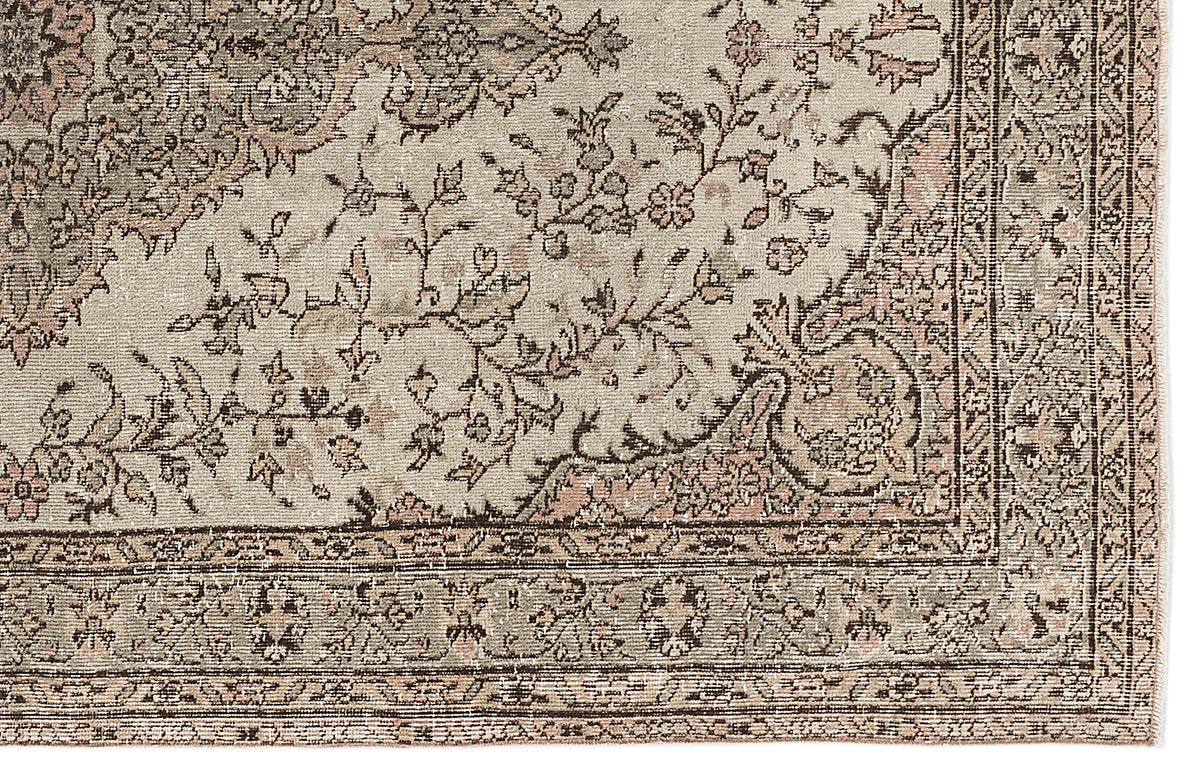 Beige and muted pink traditional rug with a distressed floral medallion pattern and intricate border.