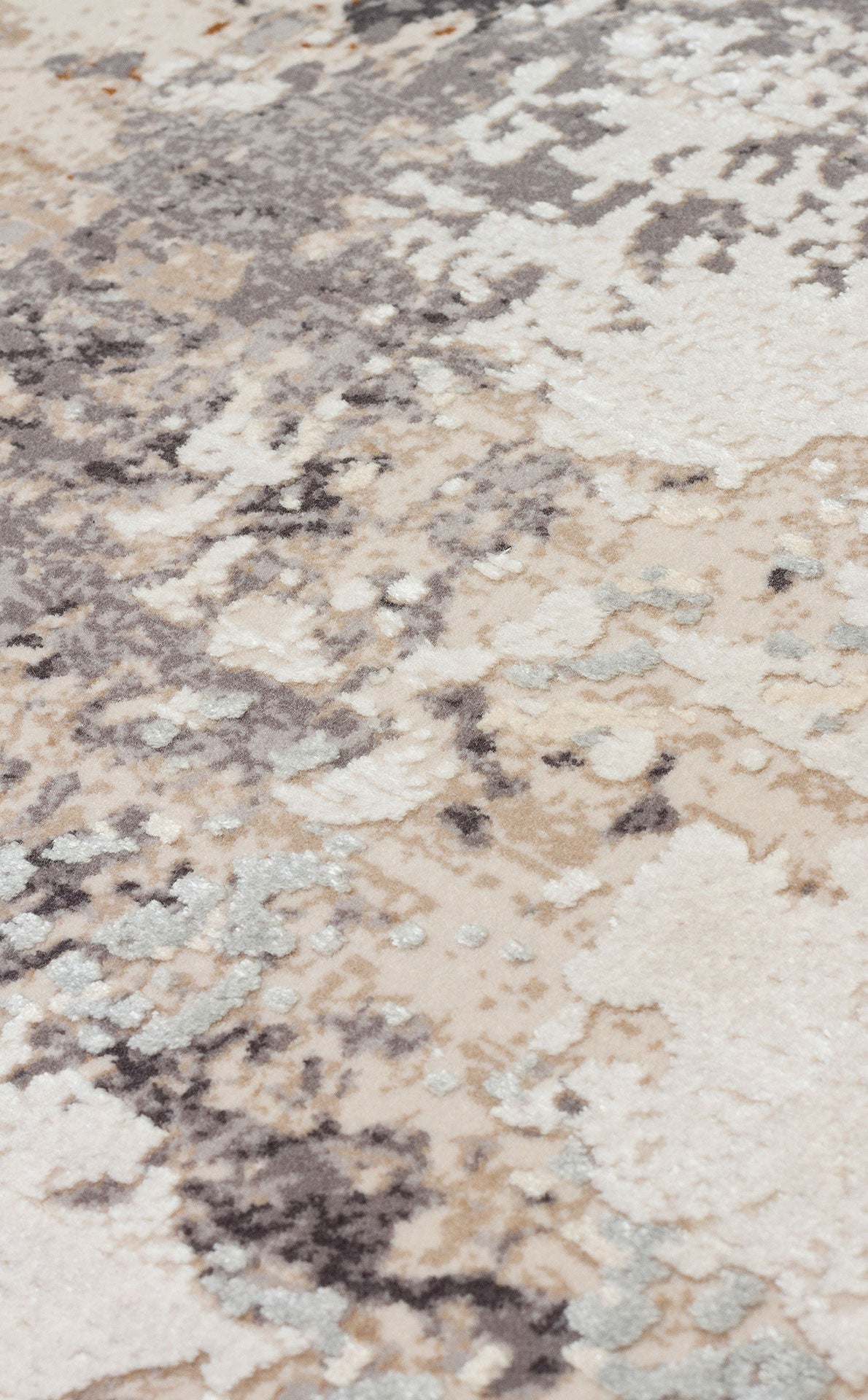 Close-up of a rug with an abstract, distressed pattern in shades of cream, grey, and light blue.
