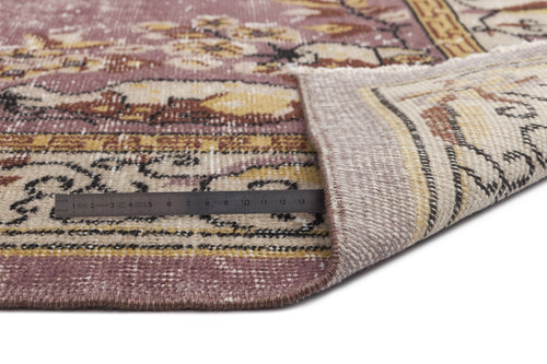 Load image 1 in gallery view. Distressed mauve and beige rug with a floral medallion pattern, shown folded with a metal ruler for scale.