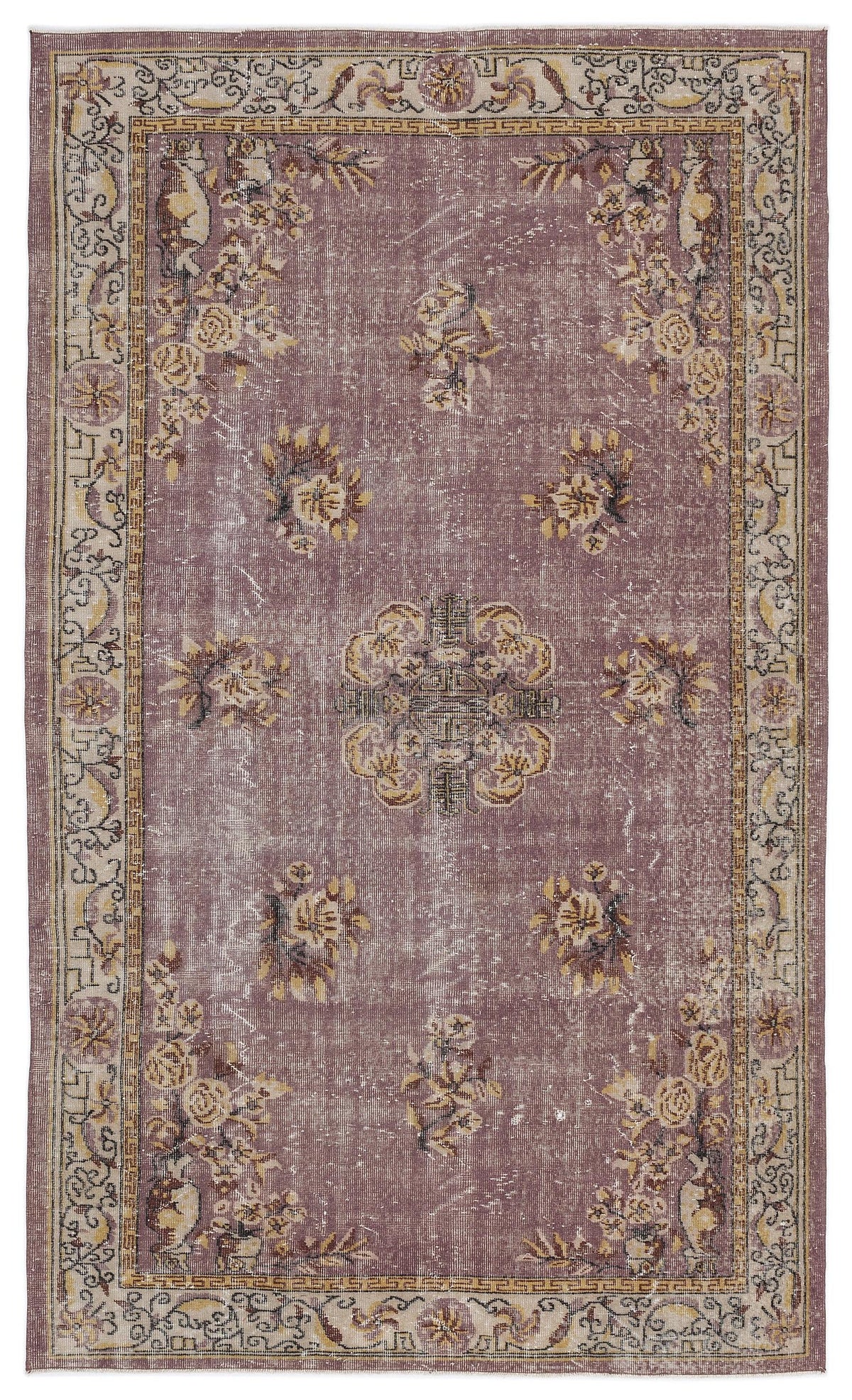 Distressed mauve rug with a central floral medallion, scattered floral motifs, and a geometric border in beige and brown.
