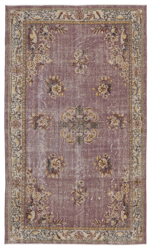 Load image 1 in gallery view. Distressed mauve rug with a central floral medallion, scattered floral motifs, and a geometric border in beige and brown.