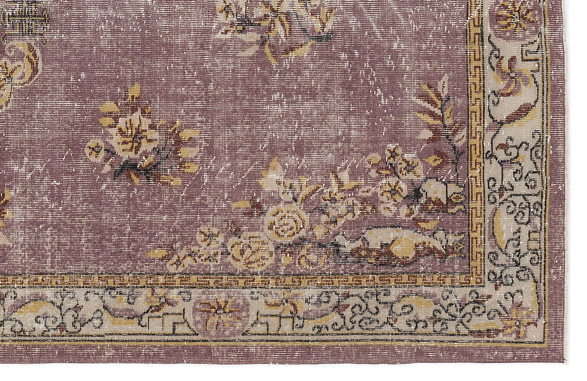 Distressed mauve rug with yellow and cream floral motifs and a geometric border pattern.