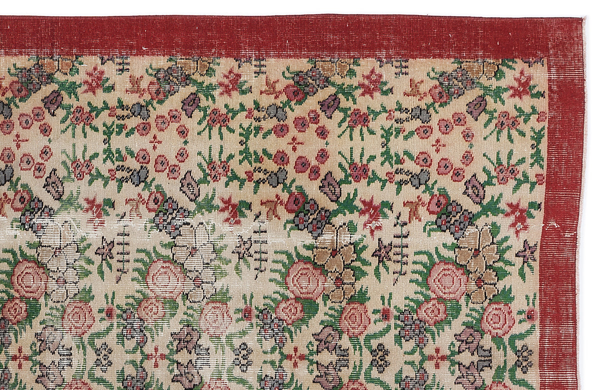 Beige rug with a red border and a repeating floral pattern in red, green, and grey on a white background.