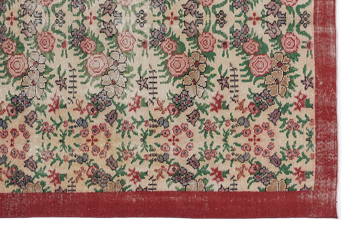 Beige rug with a multi-colored floral pattern in red, green, and purple, featuring a solid red border.