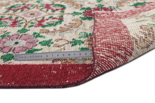Load image 1 in gallery view. Cream rug with red, green, and pink floral medallion pattern, shown folded with a metal ruler for scale.