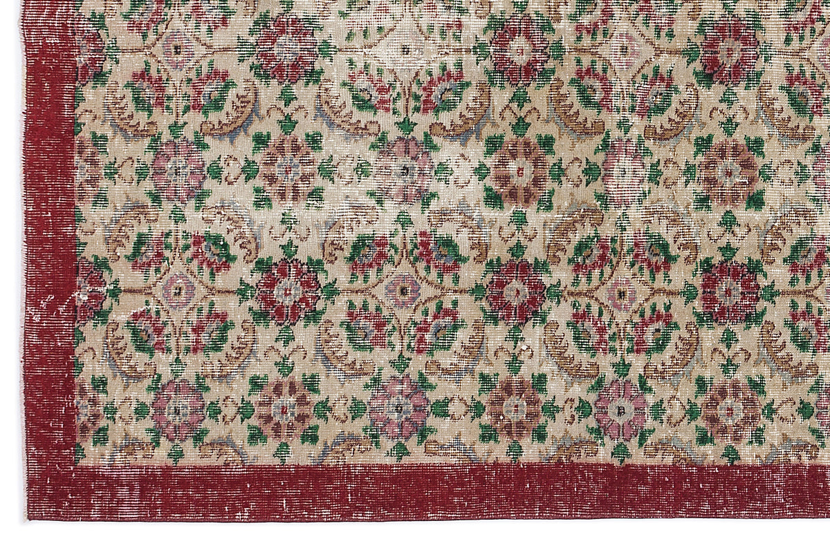 Beige rug with a distressed floral medallion pattern in red, green, and pink, featuring a solid red border.
