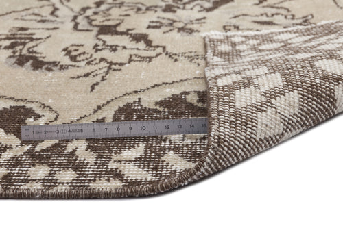 Load image 1 in gallery view. Beige and brown floral patterned rug with a folded corner revealing the woven backing and a metal ruler for scale.