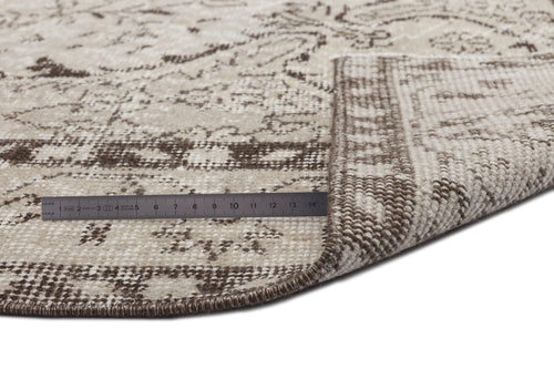 Load image 1 in gallery view. Beige and brown round rug with a distressed traditional pattern, shown with a metal ruler measuring the pile thickness.