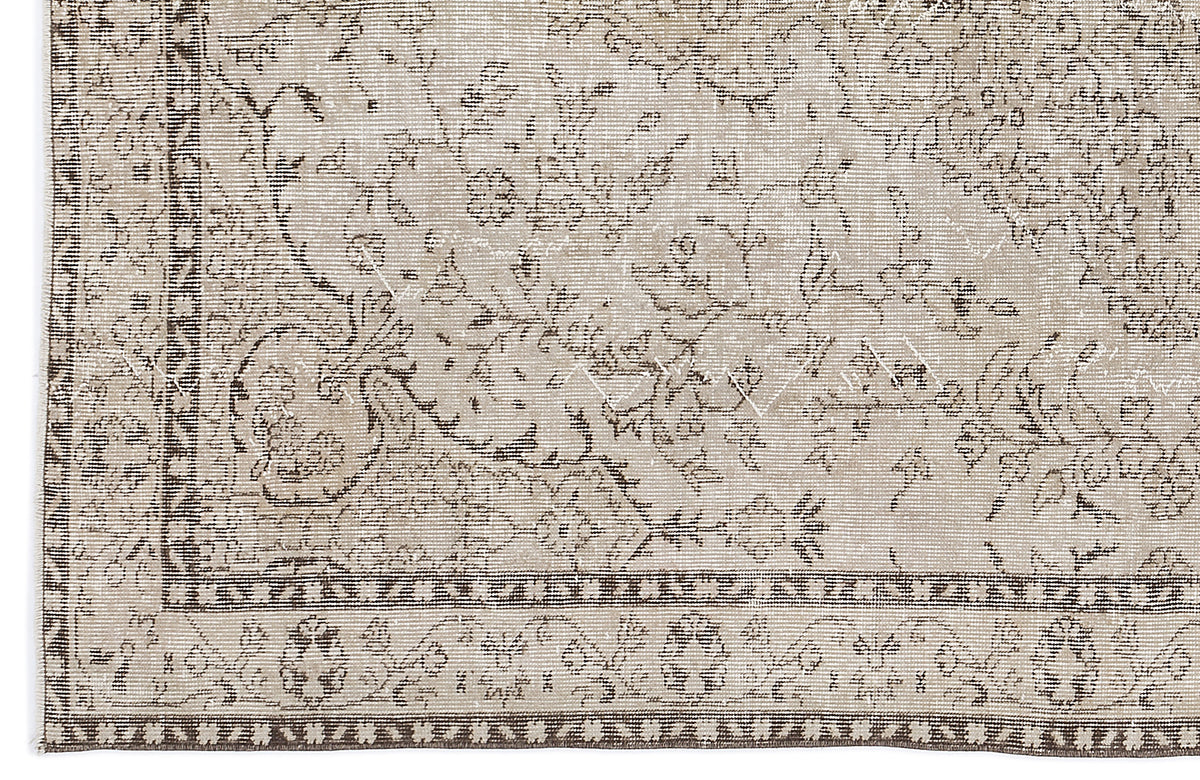Beige and brown vintage-style rug with a distressed floral medallion pattern and a geometric border.