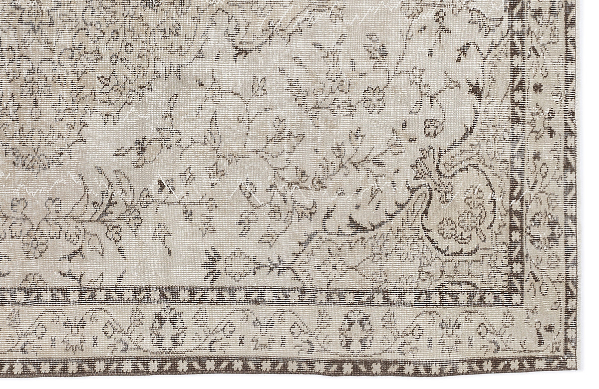 Beige and brown distressed rug with a traditional floral vine pattern and a geometric border.