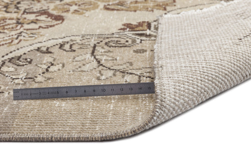 Load image 1 in gallery view. Beige and brown floral patterned rug with a corner folded back to show the woven backing and a metal ruler for scale.