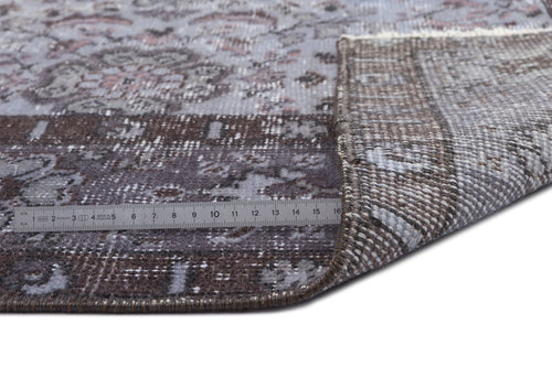 Load image 1 in gallery view. Distressed grey and brown floral medallion rug with a folded corner and a metal ruler for scale.