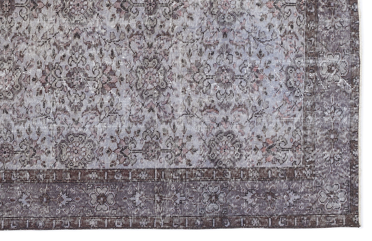 Distressed grey and charcoal rug with a traditional floral medallion pattern and a wide, ornate border.