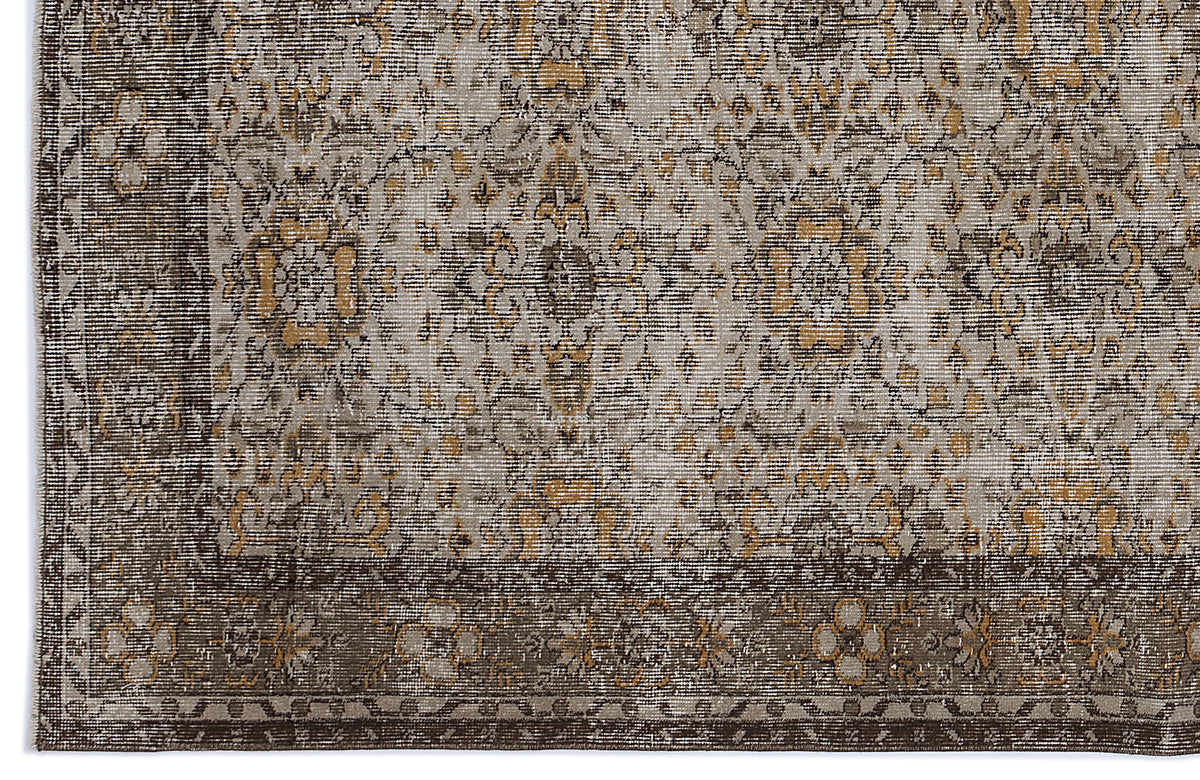 Distressed brown, grey, and ochre rug with a traditional floral medallion pattern and a wide decorative border.